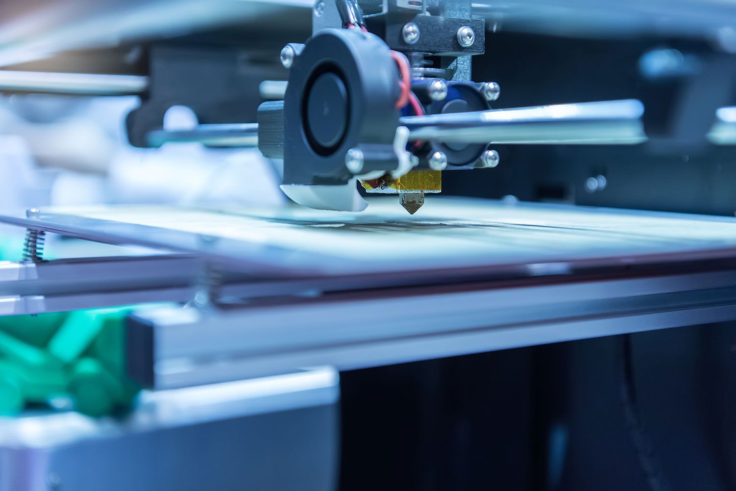 3D printer head in action on a white surface, with a blurred background.