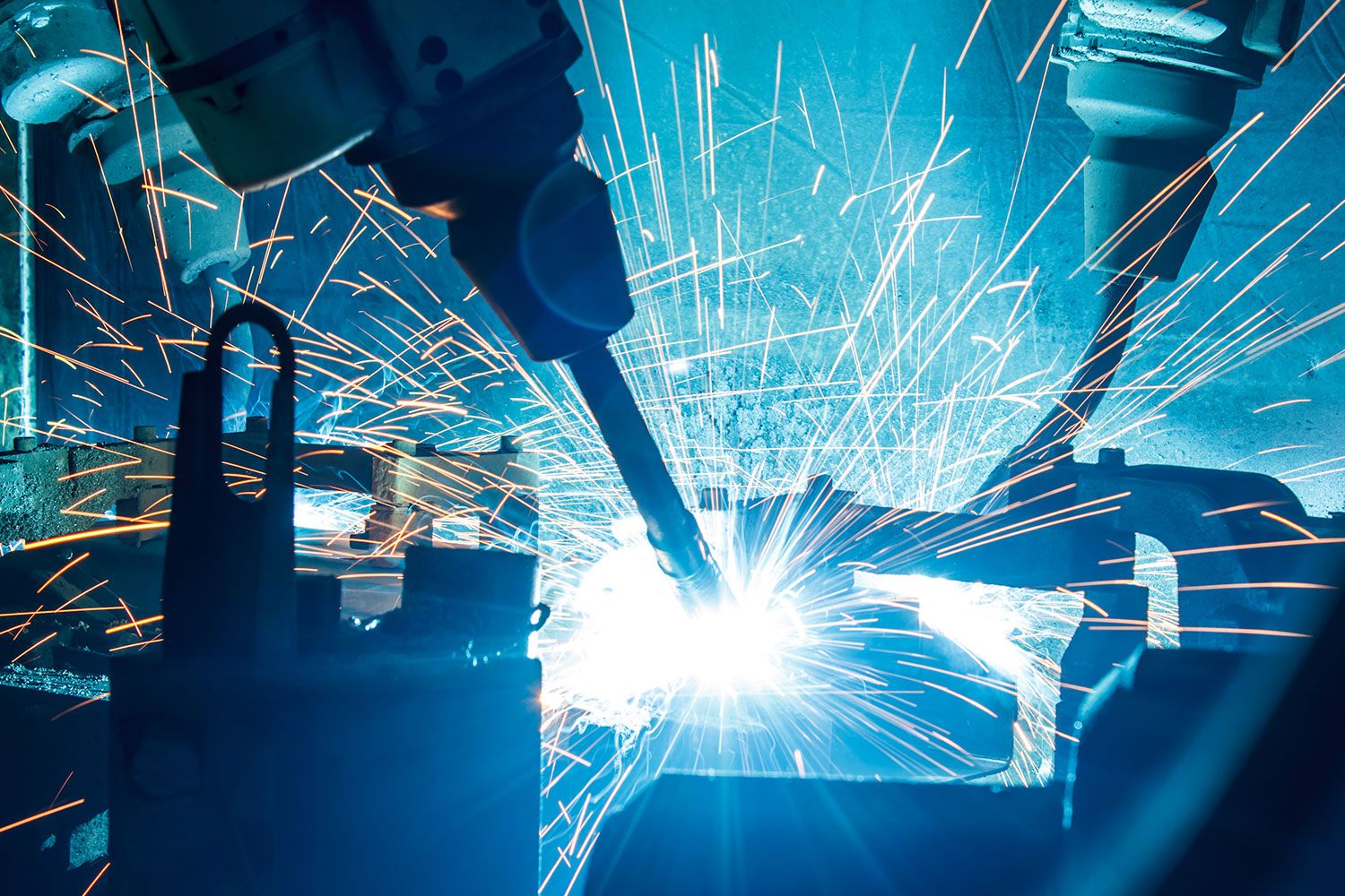 Robotic arm welding while bright sparks fly around.