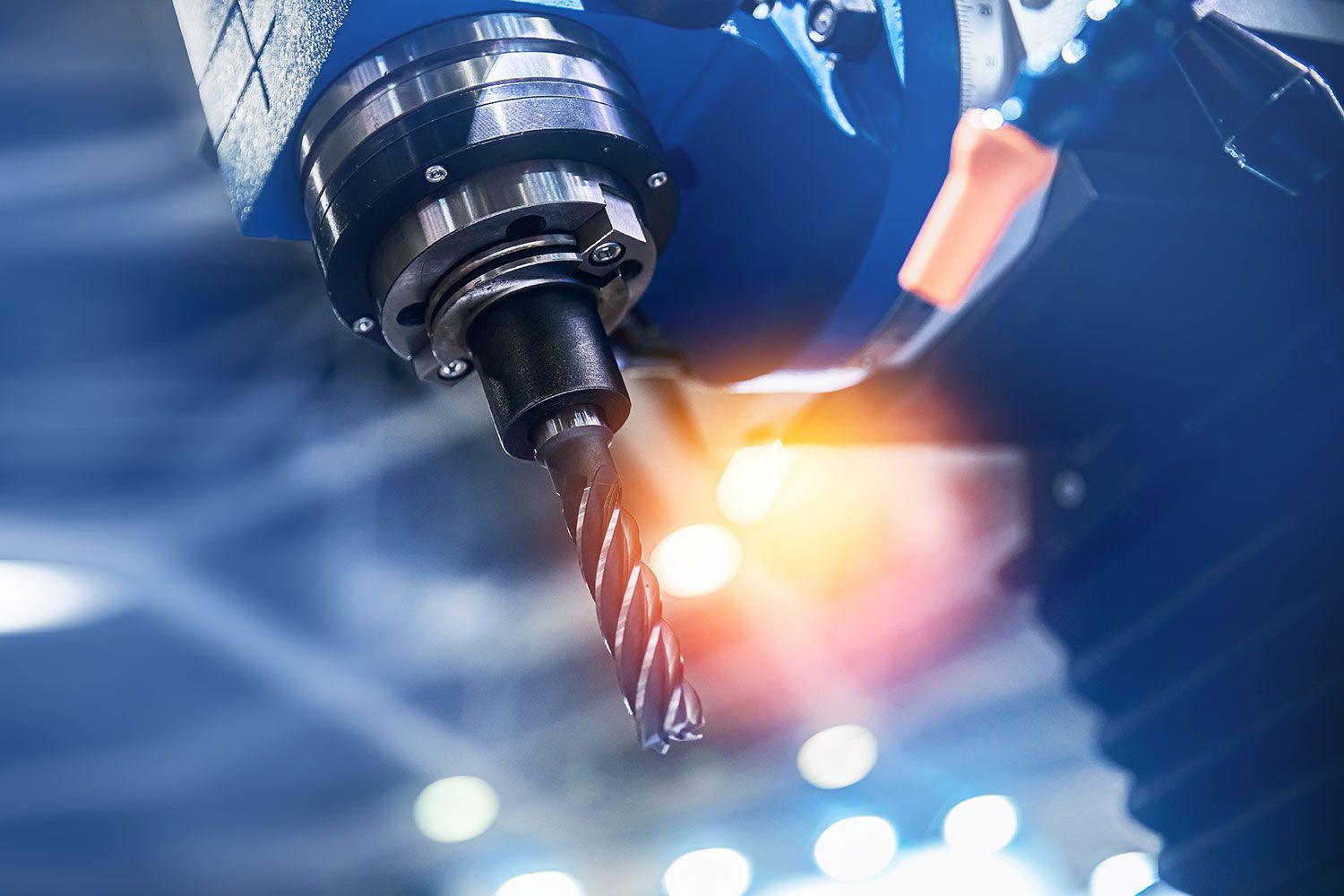 Close-up of a CNC machine drill with bright light reflection in the background.