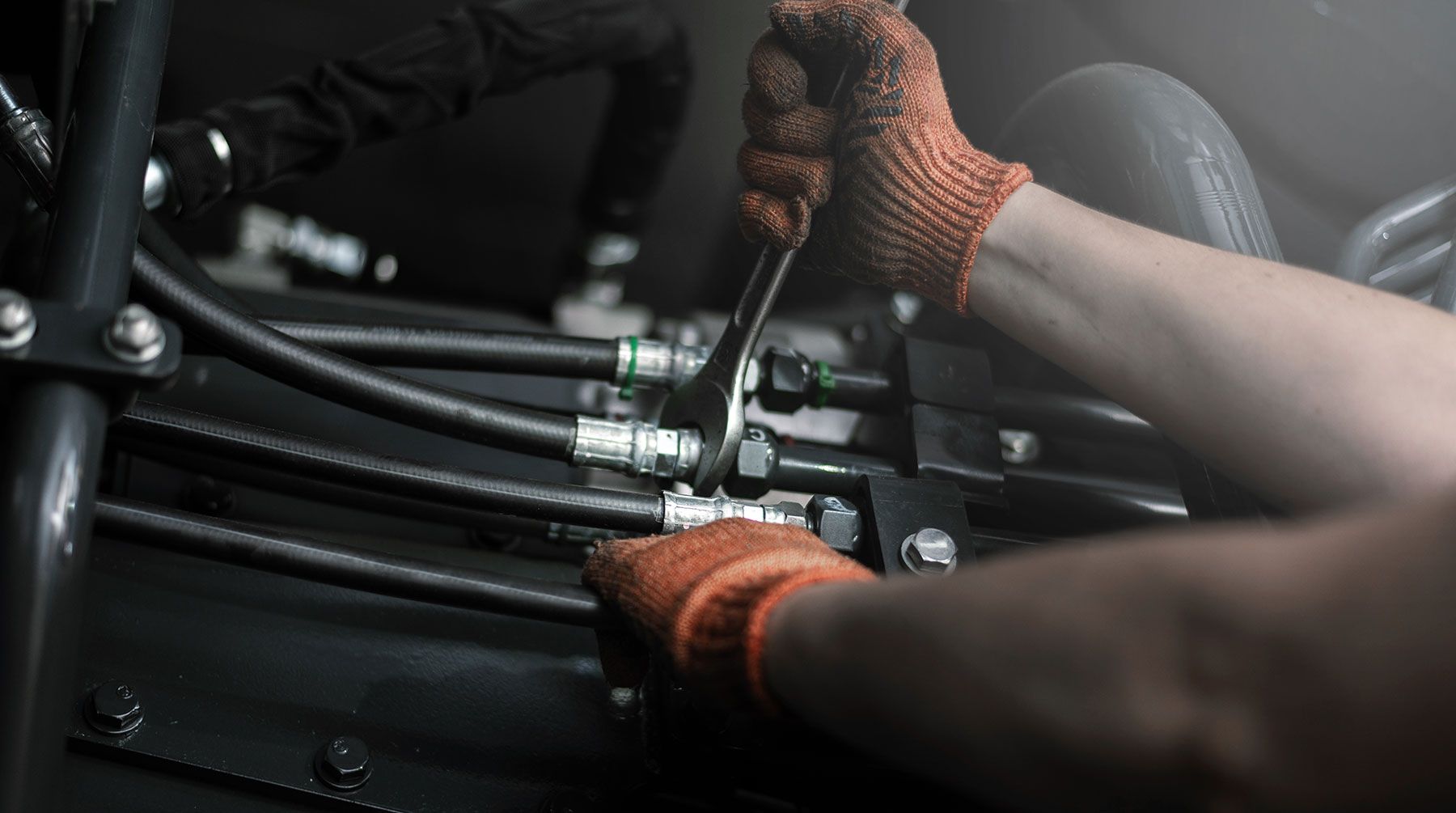Close-up of the hydraulic pipes of a heavy industrial machine being repaired.